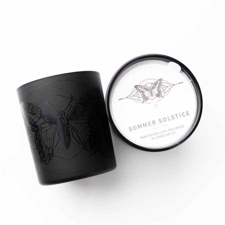 Summer Solstice Candle in black glass jar with butterfly icon, featuring scents of citrus, ginger, geraniums, patchouli, and lavender.