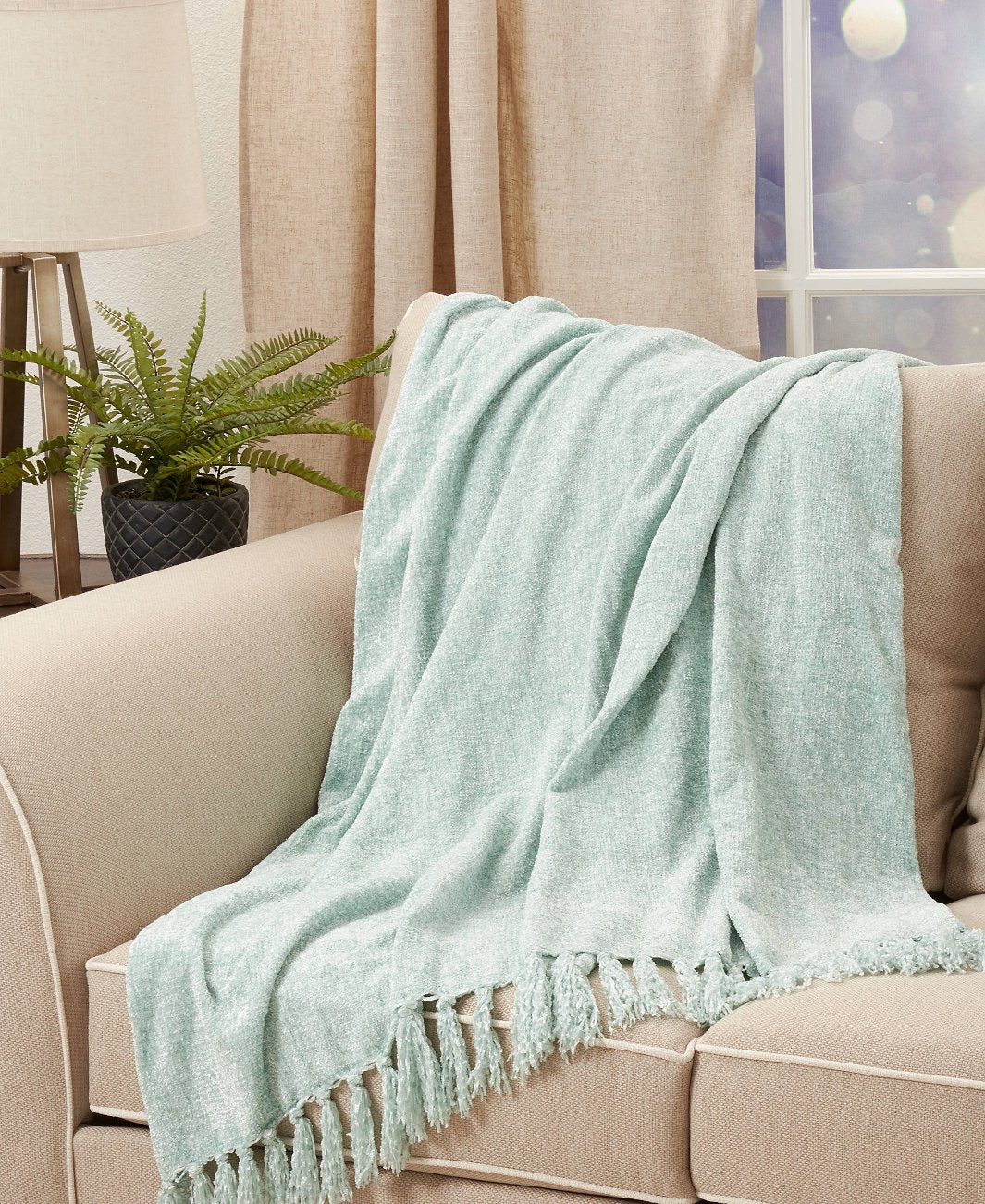 Aquamarine Chenille Fringe Throw Blanket draped over a couch, adding a stylish accent.