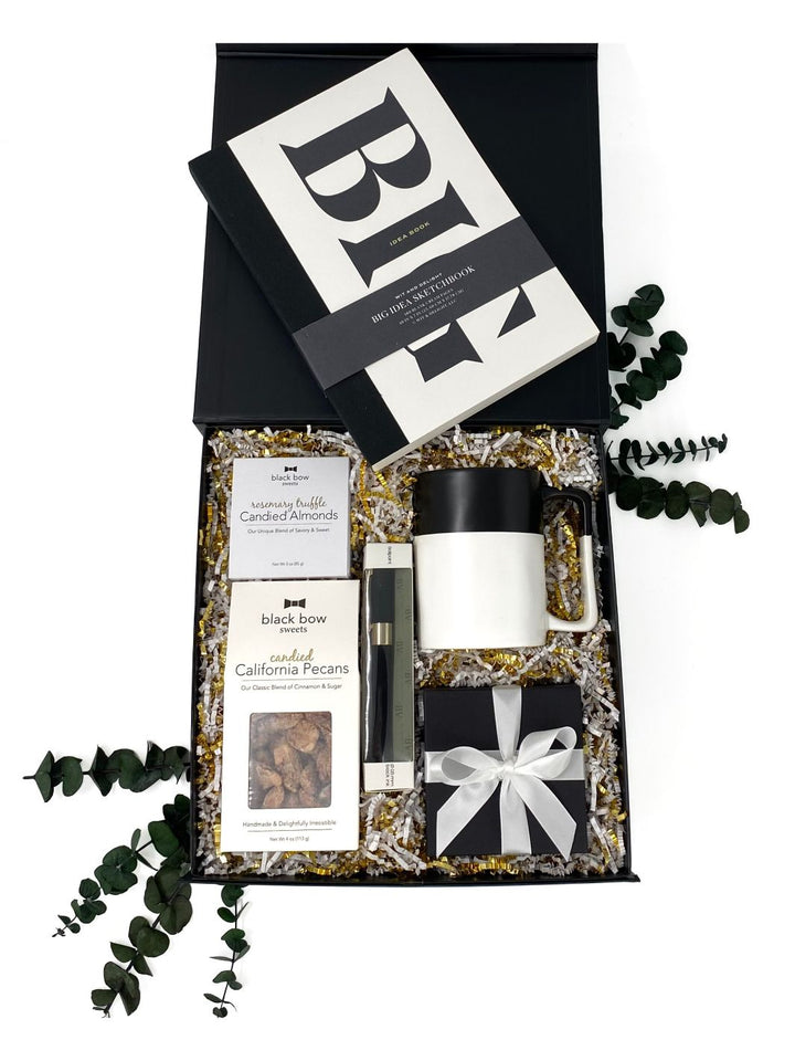Big Ideas Gift Box with sketchbook, candle, black and white mug, pen, and gourmet snacks in black World of Gifting magnetic keepsake box. 