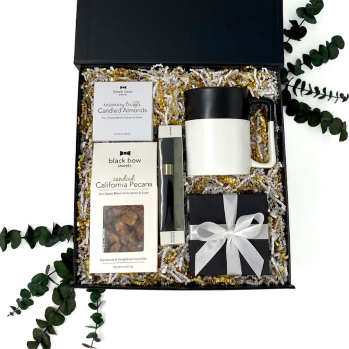 Big Ideas Gift Box interior with abundance candle, white and black mug, pen, and gourmet snacks.