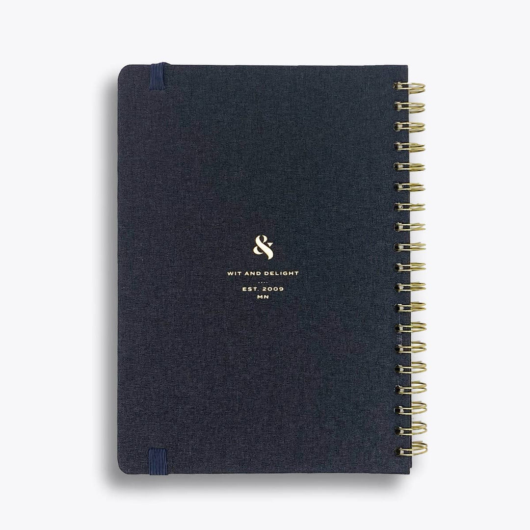 Back Cover Detail: Wit & Delight branding with 'Est 2009 MN' and gold ampersand on the black linen notebook.