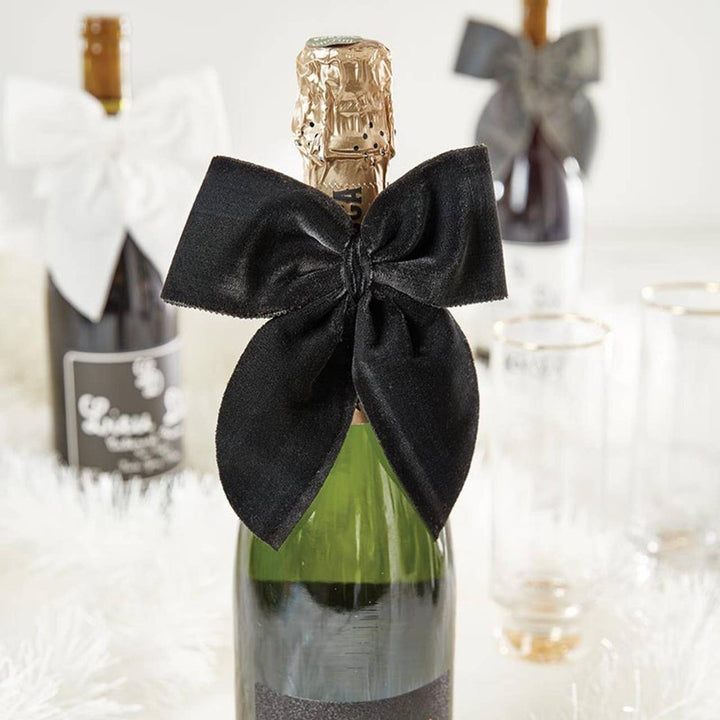Close-up of the soft black velvet bow wrapped around the neck of a champagne bottle.