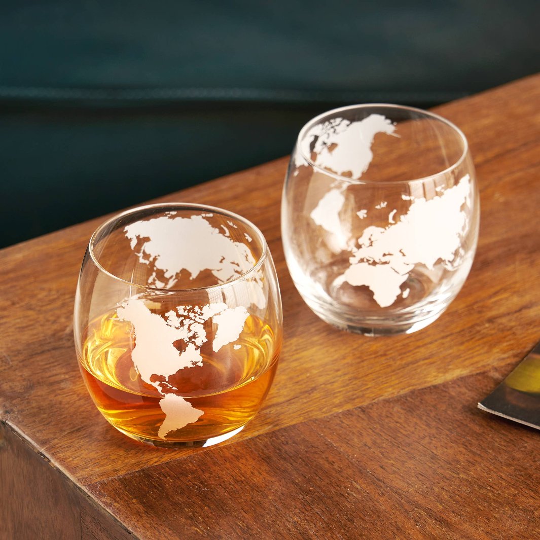 Two globe-themed rocks glasses filled with whiskey, highlighting their unique design and 12 oz capacity.