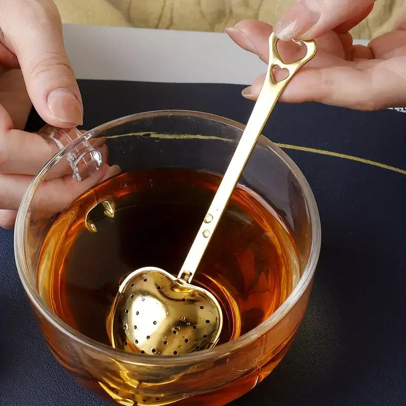 Heart-shaped golden tea infuser brewing tea, highlighting premium quality and style.