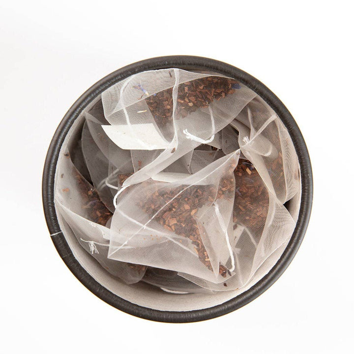 Close-up of pyramid tea bags filled with South African honeybush tea, French vanilla, and cornflower petals.
