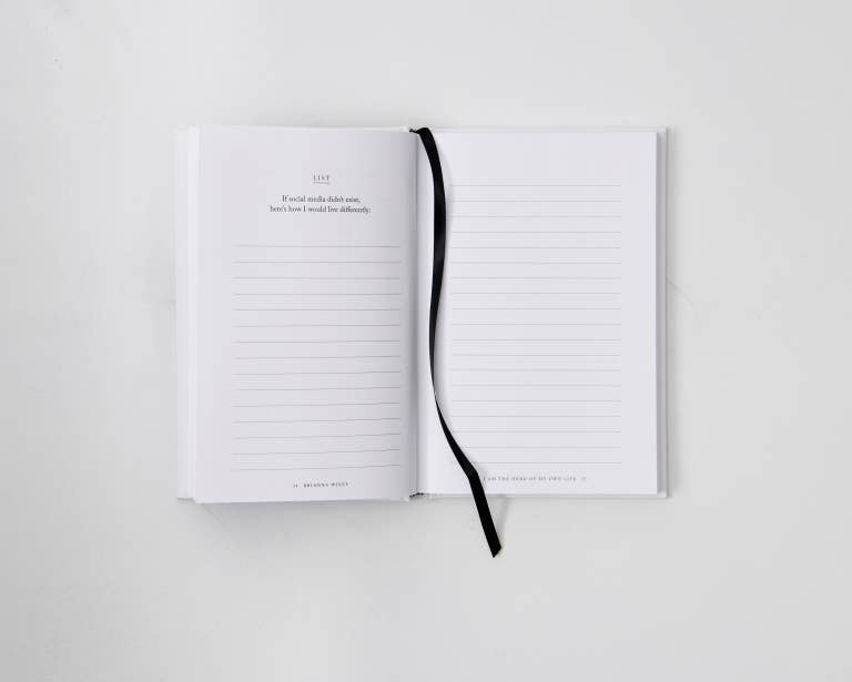 Open pages of the guided journal showcasing reflective writing prompts and black ribbon book mark.