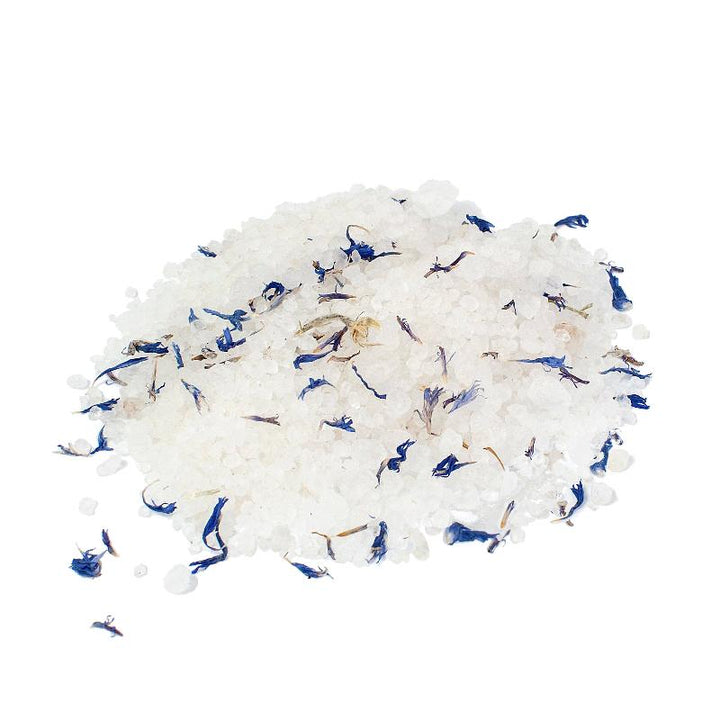 Close-up of mineral-rich Dead Sea Salt crystals mixed with blue cornflower petals, highlighting the luxurious texture and natural ingredients of the orchid-scented bath soak.