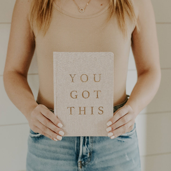 Close-up detail of luxurious gold foil lettering on stylish fabric notebook.